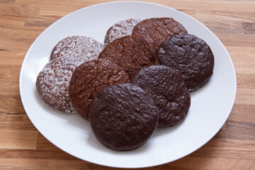Three types of German round gingerbreads on white plate.  Gingerbread covered with chocolate. Christmas desert, snack.