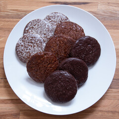 Three types of German round gingerbreads on white plate.  Gingerbread covered with chocolate. Christmas desert, snack. Top view 1x1