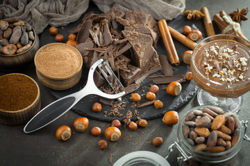 Pieces of dark chocolate and cocoa beans in composition on old background