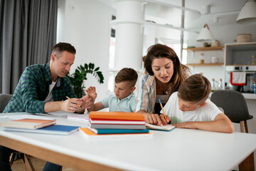 Parents helping the kids with their homework. Litlle boys learning at home.