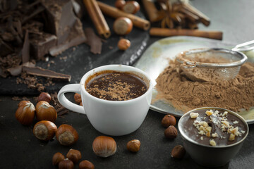 Hot chocolate on an old background in a composition with cocoa beans and nuts.