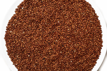 Top view of raw buckwheat on a plate on a white background. Healthy food, great breakfast, wholesome food. A traditional dish
