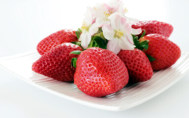 Intensive red strawberries on a white plate.