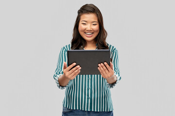 Fototapeta premium technology and people concept - happy asian woman using tablet computer over grey background