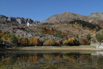 Autumn mountain forest lake house reflection in water landscape.