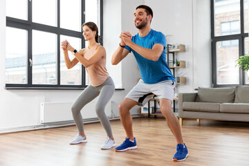 sport, fitness, lifestyle and people concept - smiling man and woman exercising and doing squats at...