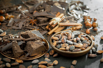 Dark chocolate in a composition with cocoa beans and nuts, on an old background.