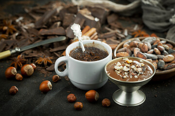 Hot chocolate on an old background in a composition with cocoa beans and nuts.