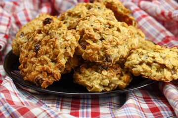 Black plate with homemade oatmeal cookies with raisins on a black background