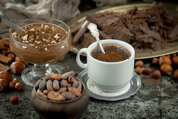 Hot chocolate on an old background in a composition with cocoa beans and nuts.