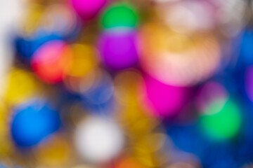 Defocused glowing Xmas balls holiday decorations, abstract blurry bokeh background effect. Out of focus colorful Happy New Year lights celebration texture for use at graphic design.