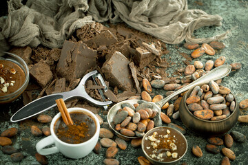 Pieces of dark chocolate and cocoa beans in composition on old background