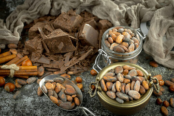 Dark chocolate in a composition with cocoa beans and nuts, on an old background.