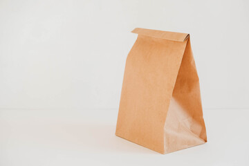 Closed disposable package made of brown kraft paper on a white background. Copy, empty space for text