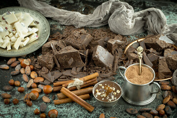 Dark chocolate in a composition with cocoa beans and nuts, on an old background.