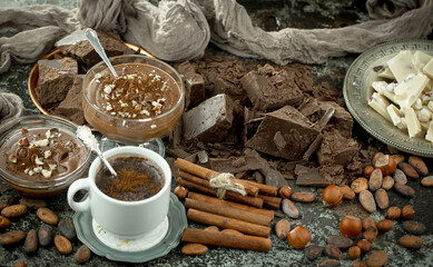 Hot chocolate on an old background in a composition with cocoa beans and nuts.