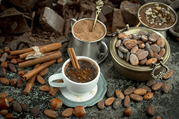 Hot chocolate on an old background in a composition with cocoa beans and nuts.