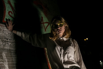 Female at night with a graffiti background. Low key