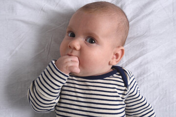 the baby who puts his hand in his mouth to suck his finger