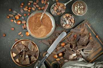 Fototapeta na wymiar Pieces of dark chocolate and cocoa beans in composition on old background