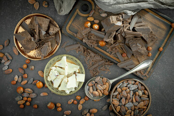 Pieces of dark chocolate and cocoa beans in composition on old background