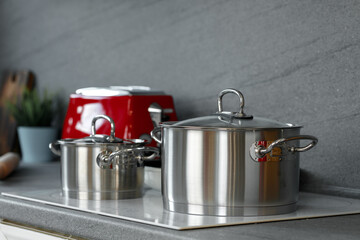 Still life photo of metal casseroles on induction stove in kitchen