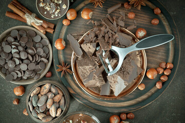 Pieces of dark chocolate and cocoa beans in composition on old background