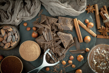 Pieces of dark chocolate and cocoa beans in composition on old background