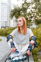 Full-length sitting portrait of sporty woman in roller-skates on the street