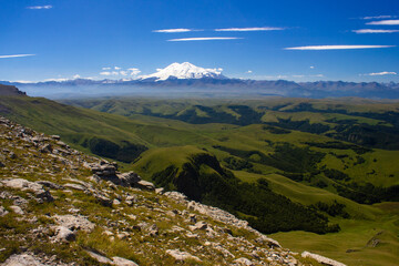 An excellent view from the plateau to the extinct volcano and the snowy peak of Mount Elbrus. Below is a green gorge