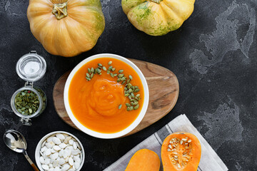 Top view of pureed pumpkin soup in a white bowl on dark table