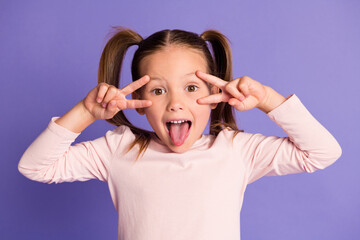 Photo of playful cute small child make face show v-sign funky mood isolated on purple color background