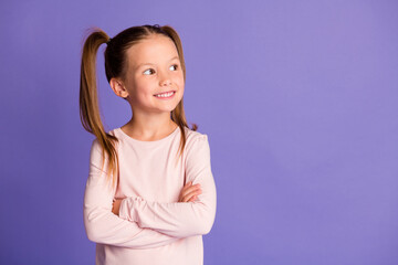 Photo of attractive little girl look empty space folded arms wear sweatshirt isolated on purple color background