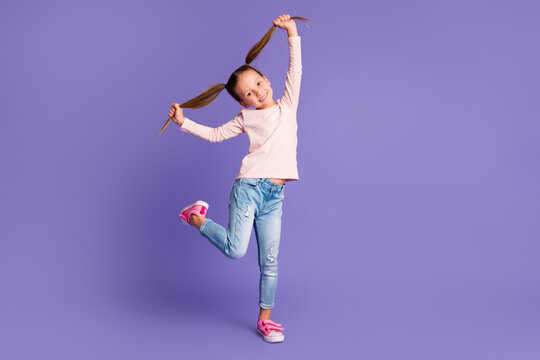 Full size photo of careless happy girl hold hands pigtails wear jeans sweater isolated on purple color background