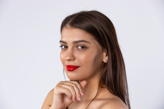  A beautiful brunette model with red lips looks at the camera. Beauty and makeup concept. Photo on white background