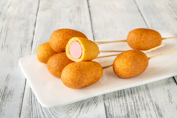 Corn dogs on white serving plate