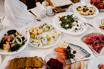 Serves dinner on a festive table. Food, Salads, Meat, Fish Meals. Festive table at wedding banquet. Decor. Details.