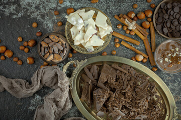 White and black chocolate on the table in a composition with nuts and cocoa beans.