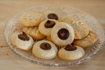 Light brown beige baked peanut cookies filled with dark chocolate, one by one on the plate, tasty Christmas sweets ready to eat