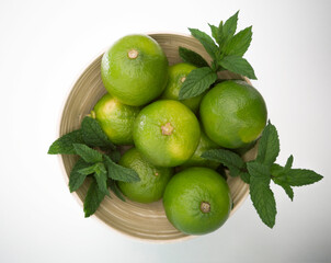 Colorful juicy limes in the bowl on the white background.