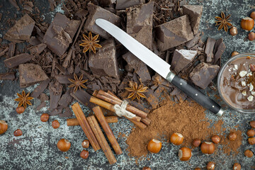 Pieces of dark chocolate and cocoa beans in composition on old background