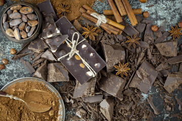 Pieces of dark chocolate and cocoa beans in composition on old background