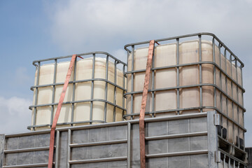 white ibc containers on transport truck with blue sky. chemical container on delivery with safety belt.