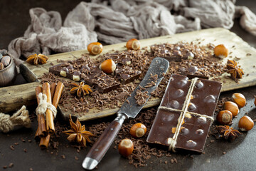 Pieces of dark chocolate and cocoa beans in composition on old background