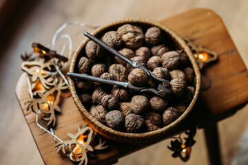 Whole walnuts in shell in bowl, on the small wooden chair and christmas lights around