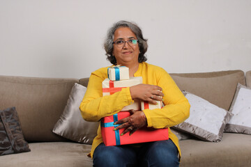 Obraz premium Portrait of a happy indian woman holding a stack of gifts.