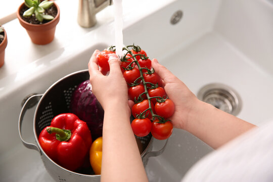 Woman washing fresh cherry tomatoes in kitchen sink, closeup - Powered by Adobe