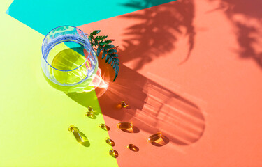 Glass of clear transparent water on a colorful background in natural light with harsh shadows.