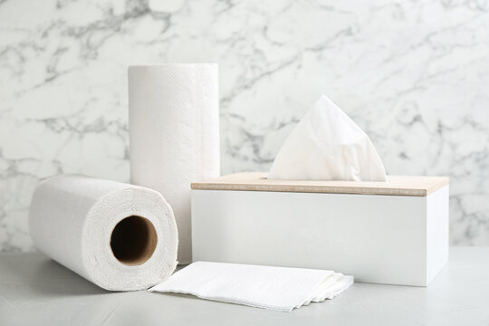 Clean napkins, box with tissues and rolls of paper towels on light table
