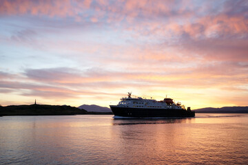 Fototapeta na wymiar A ship entering Oban harbour in the Scottish highlands during sunset